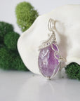 Side angle of raw amethyst pendant showing artisan wire wrapped sterling silver detail
