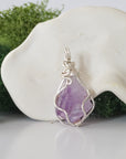 Back angle look at simple raw amethyst pendant with silver wire wrapping