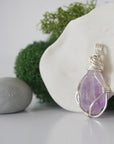 Detailed side angle view of simple raw amethyst pendant in silver wire