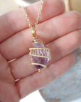 Raw amethyst point pendant necklace on gold plated brass chain held in hand for size reference