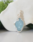 Back angle look at simple raw aquamarine pendant with silver wire wrapping