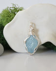 Detailed front angle view of simple raw aquamarine pendant in silver wire