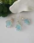 Three raw aquamarine pendants showing natural variation in stone size, shape, and pale blue tone — each one of a kind, March birthstone, 925 sterling silver wire wrapped, Designs by Nature Gems