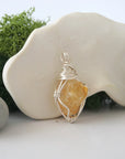 Detailed side angle view of simple raw citrine pendant in silver wire