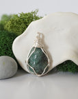 Detailed front angle view of simple raw emerald pendant in silver wire