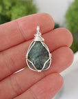 Simple raw emerald pendant shown in hand for size reference