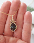 Raw garnet necklace in 14k gold filled shown in hand for size reference. Artisan January birthstone pendant by Designs by Nature Gems.