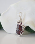 Side angle of raw garnet pendant showing artisan wire wrapped sterling silver detail