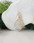 Detailed front angle view of simple raw opal pendant in silver wire