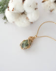Raw peridot necklace in 14k gold filled laying flat. Handcrafted August birthstone jewelry for women by Designs by Nature Gems.