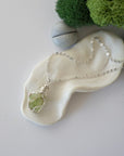 Simple raw peridot necklace with silver plated brass chain laying flat