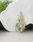 Back angle look at simple raw peridot pendant with silver wire wrapping