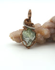 Front view of raw peridot pendant for men — natural sage olive green crystal with pale markings, antique bronze and dark silver wire wrap, handcrafted August birthstone jewelry