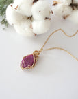 Raw pink ruby necklace in 14k gold filled laying flat. Handcrafted July birthstone jewelry for women by Designs by Nature Gems.