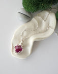 Simple raw pink ruby necklace with silver plated brass chain laying flat