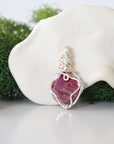Back angle look at simple raw pink ruby pendant with silver wire wrapping