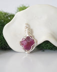 Detailed front angle view of simple raw pink ruby pendant in silver wire