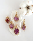 Five raw pink ruby pendants in 14k gold filled, showing natural variation in size, shape, and color. Handcrafted July birthstone jewelry by Designs by Nature Gems.