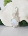 Close up front view of raw rainbow moonstone crystal with detailed 925 sterling silver wire wrapping