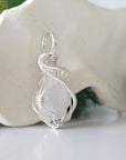 Side angle of raw rainbow moonstone pendant showing artisan wire wrapped sterling silver detail