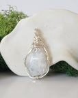 Back angle look at simple raw rainbow moonstone pendant with silver wire wrapping
