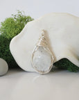 Detailed front angle view of simple raw rainbow moonstone pendant in silver wire