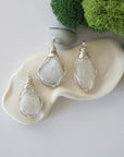 Three different raw rainbow moonstone pendants displayed for variation reference