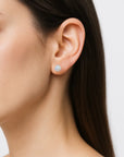 Model wearing raw rainbow moonstone stud earrings on 925 sterling silver posts, minimalist June birthstone earrings for everyday wear.