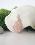 Detailed front angle view of simple raw rose quartz pendant in silver wire