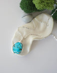 Raw turquoise necklace with simple silver wire wrapping on silver plated chain, minimalist crystal pendant flat lay