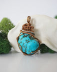 Front view of raw turquoise pendant showing detailed antique bronze copper wire wrapping, handmade artisan jewelry