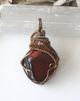 Detailed view of natural red tiger's eye pendant, artisan wire wrapped by Designs by Nature Gems.