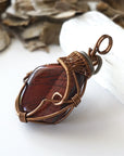 Left side angle detail of natural red tiger's eye pendant, artisan wire wrapped by Designs by Nature Gems.