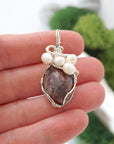 Ruby and freshwater pearl pendant necklace in hand for size reference, silver wire wrapped, handcrafted gemstone jewelry