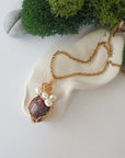 Ruby and freshwater pearl pendant on gold plated brass chain laying flat, handmade wire wrapped jewelry for women
