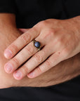 Man wearing a natural sapphire ring with antique bronze and dark silver wire wrap — handcrafted all-genders birthstone jewelry