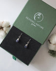 Sapphire sterling silver drop earrings in branded Designs by Nature Gems jewelry box, showcasing handcrafted faceted sapphire and sterling silver wire wrapping