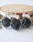 Three silver wire wrapped shungite and freshwater pearl pendants showing natural stone variation, artisan jewelry for women