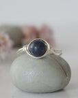 Front-angle detail of silver wire-wrapped sapphire ring showing the classic minimalist artisan setting for women