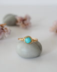 Front view of simple turquoise ring in gold plated copper showing 6mm polished stone and handmade wire wrapping detail