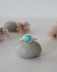 Front view of simple turquoise ring in silver plated copper showing 6mm polished stone and handmade wire wrapping detail