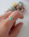 Simple turquoise ring for women in gold plated copper worn on hand showing 6mm polished stone and minimalist wire wrap
