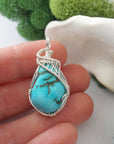 Raw turquoise pendant in hand showing size, sterling silver wire wrapped crystal necklace for women scale reference