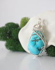 Side angle of sterling silver raw turquoise pendant showing intricate wire wrap detail and natural crystal texture