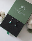 Turquoise sterling silver drop earrings in branded Designs by Nature Gems jewelry box, showcasing handcrafted faceted turquoise and sterling silver wire wrapping