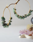Close detail of emerald hoop earrings showing natural emerald chips and artisan wire wrapping in warm gold copper