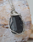 Right angle detail of raw black tourmaline necklace for men – highlights artisan dark silver copper wire wrapping and bold stone texture.