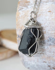 Left angle detail of raw black tourmaline necklace for men – close-up of wire wrapping and deep black tourmaline.