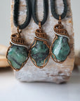 Three raw emerald pendants for men – showing natural variation in size, shape, and green shade, black leather cord.