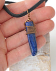 Lapis lazuli point necklace for men in hand for size reference – genuine blue stone, antique bronze copper wire, masculine design.